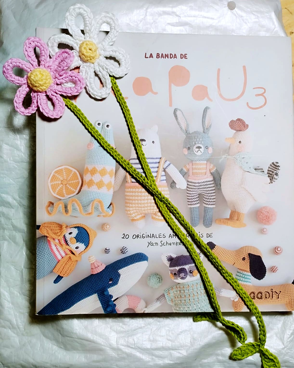 Marcapaginas de flores de crochet con tallo largo sobre libro de amigurumis