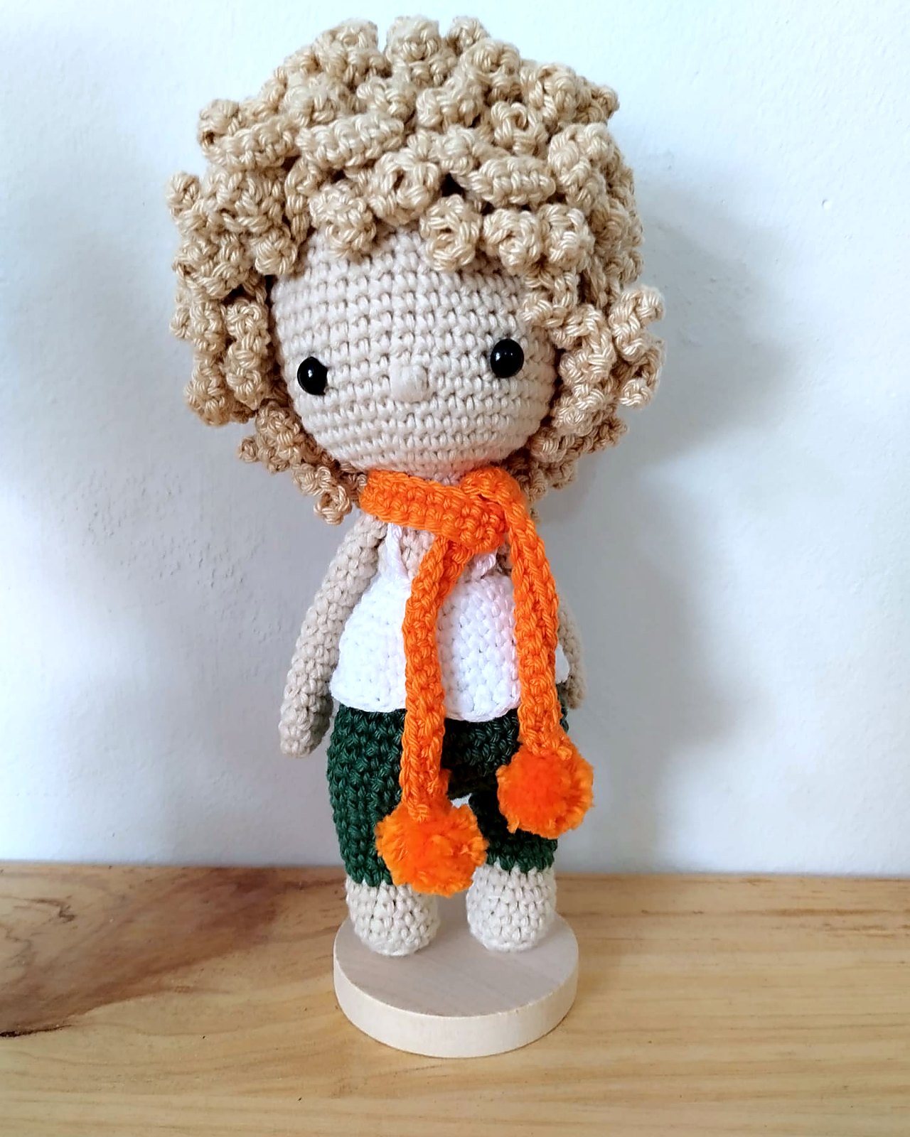 Muneco amigurumi de pelo rizado con bufanda naranja