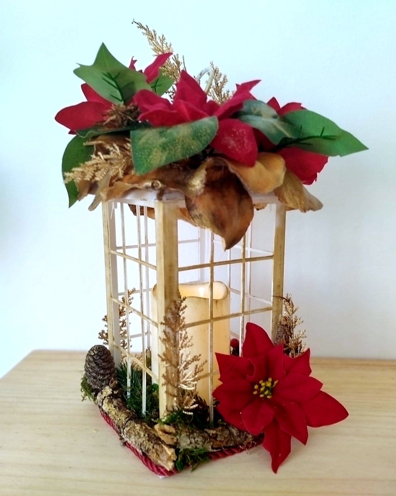 Farol navideno iluminado con flores de pascua, plano cenital