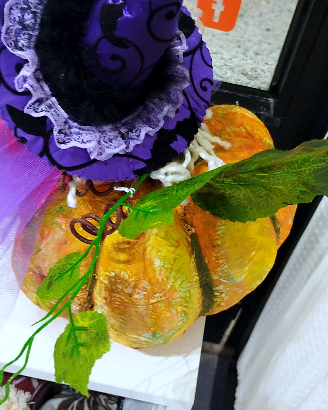 Sombrero de bruja morado sobre calabaza iluminada