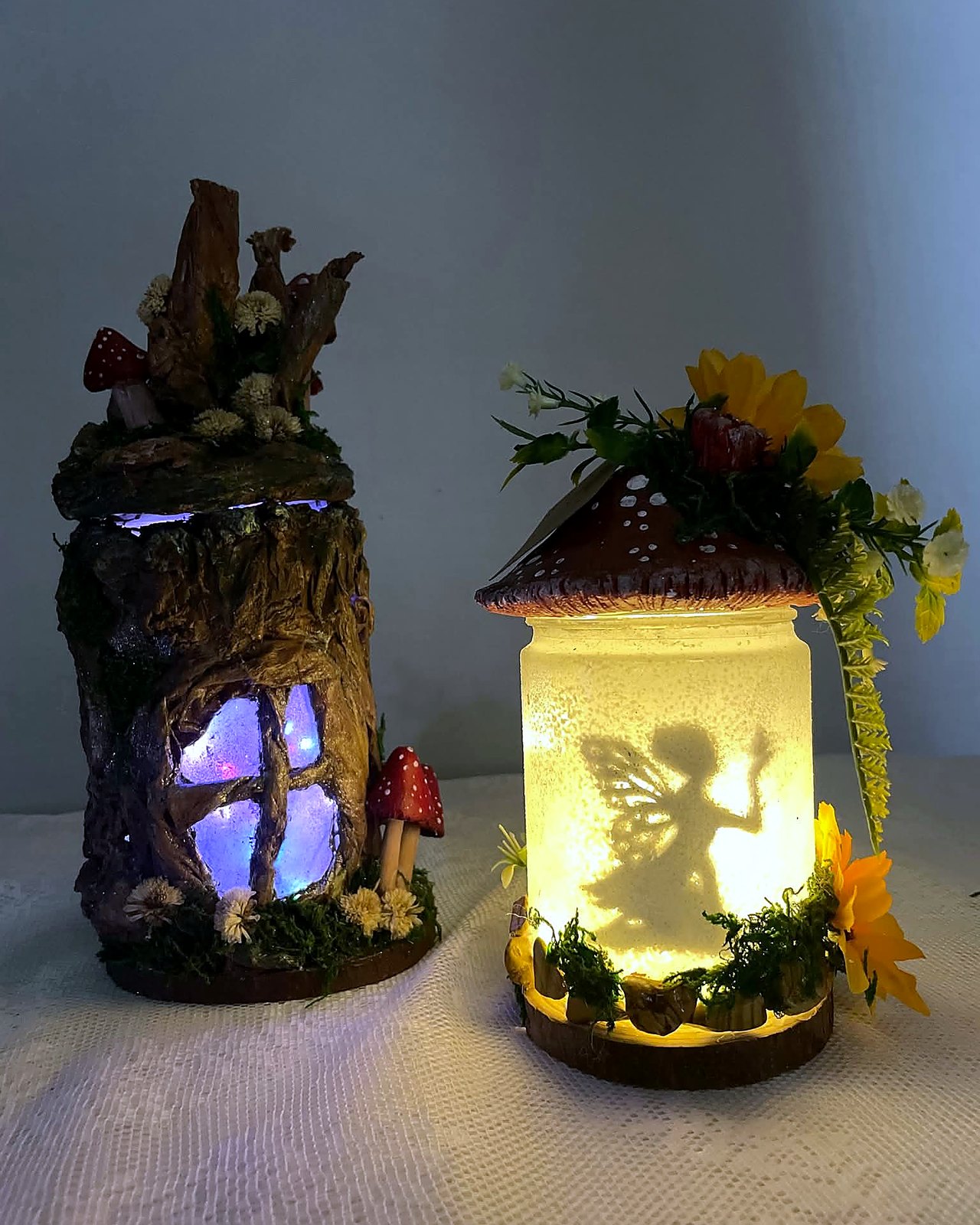 Dos lamparas de hada iluminadas: tronco con puerta magica y tarro con silueta de hada. Rotulado por Mapi como Lamparas de hada