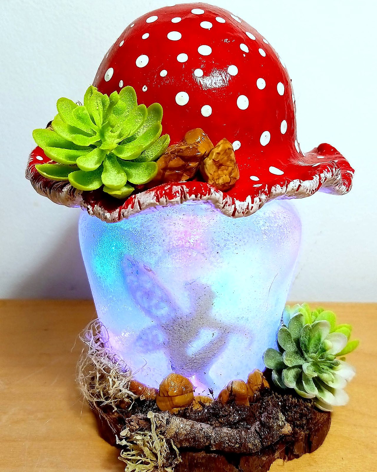 Lampara de seta amanita iluminada con suculentas sobre base de corteza