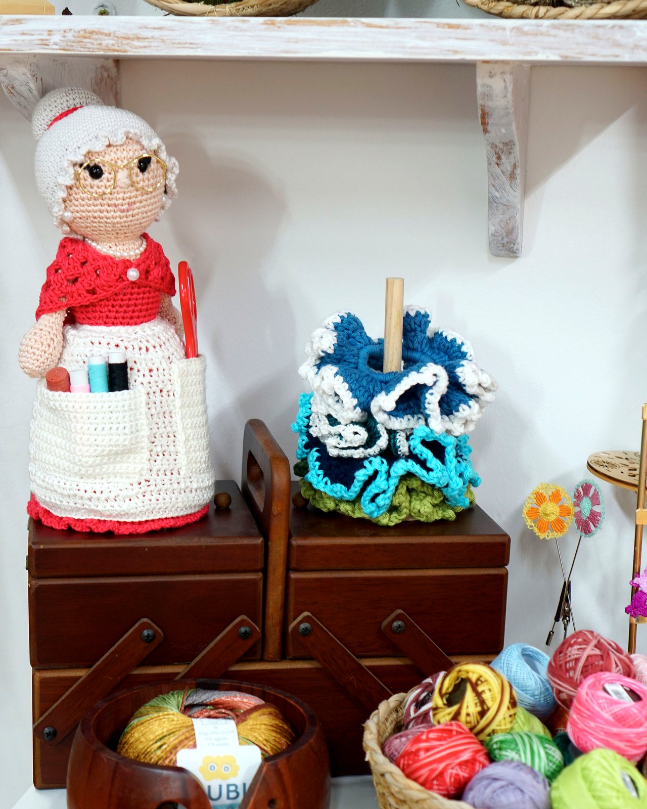 Abuelita roja sobre costurero antiguo junto a pulpo azul y cestas de lana