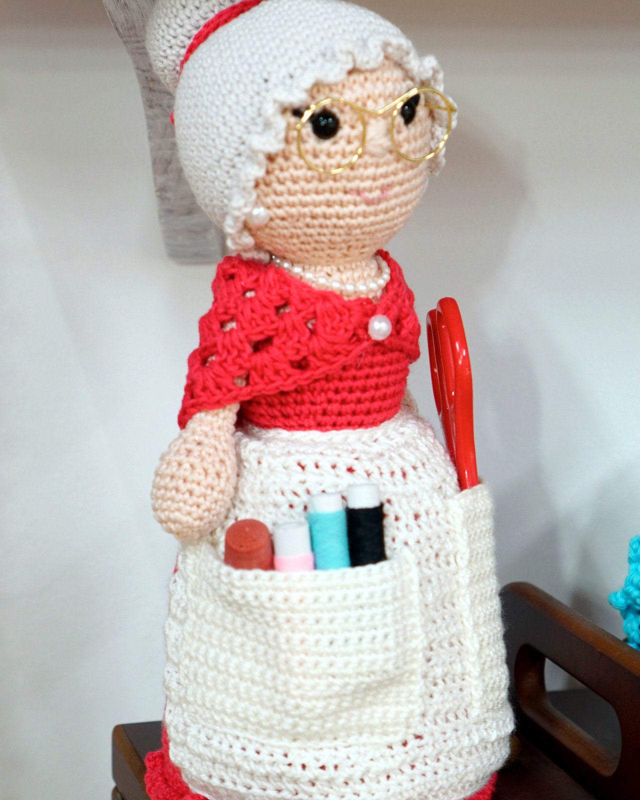 Abuelita roja amigurumi con gafas y delantal, plano medio