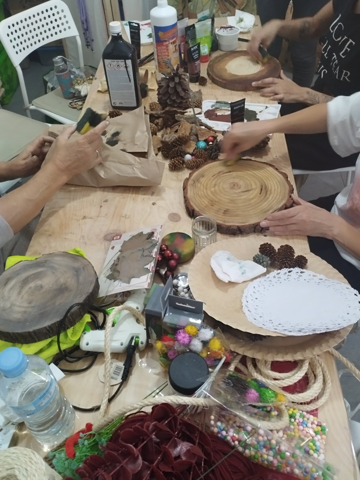 Mesa de trabajo del taller de Navidad con rodajas de madera y piñas