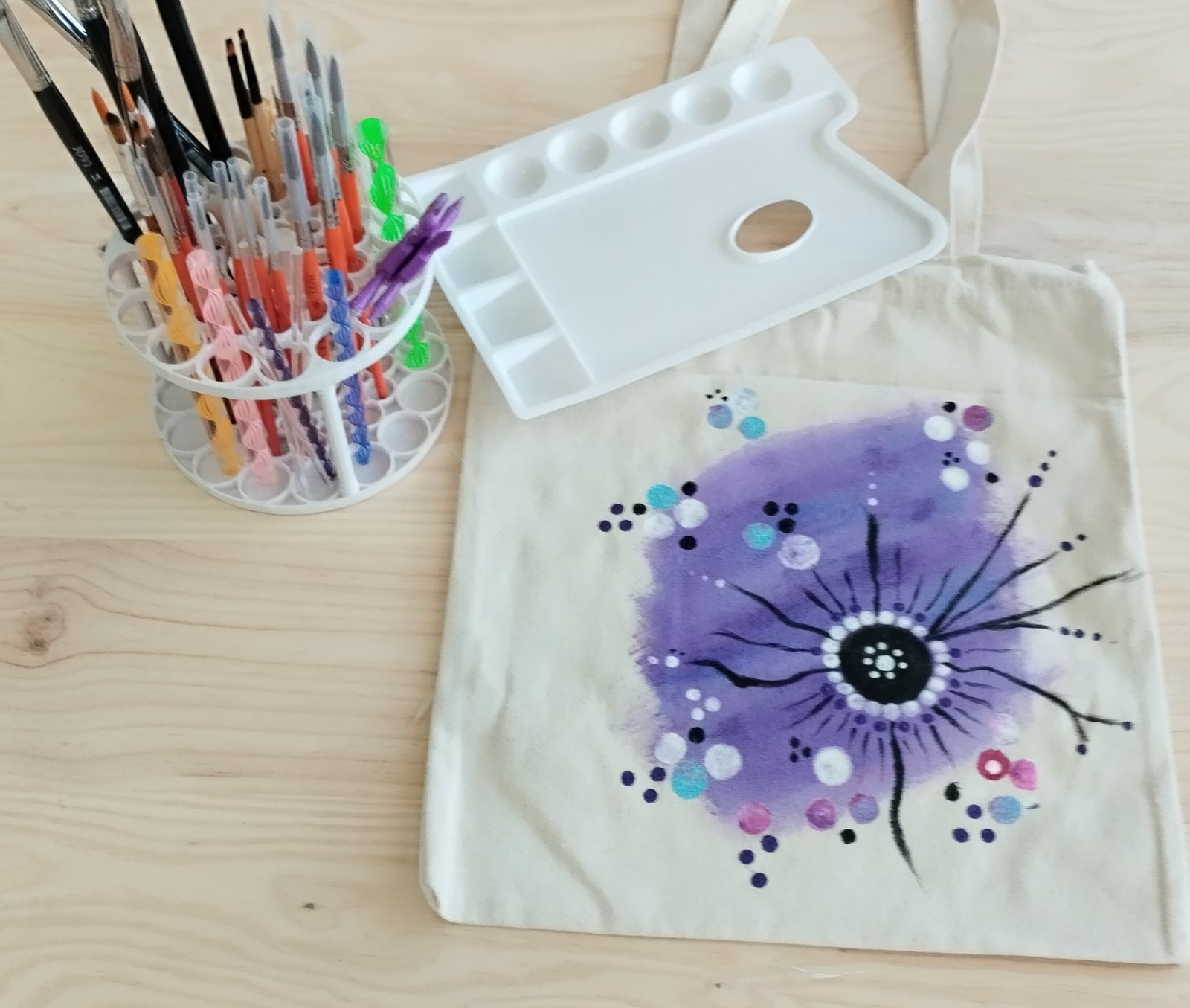 Bolsa de tela pintada a mano con pinceles y paleta en el taller